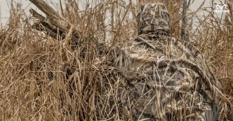 a hunter wearing realtree max 7 camo in the marsh