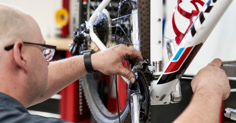 A ERLEBNISWELT-FLIEGENFISCHEN bike expert repairing a Trek bike