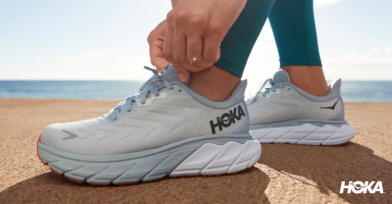 a runner adjusting her hoka running shoes