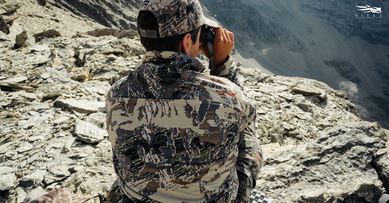 a hunter wearing sitka open country camo pattern out scouting