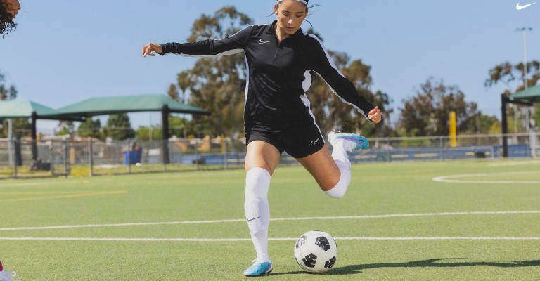 a girl kicking a soccer ball on the field