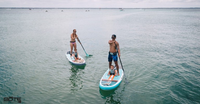 a family out paddle boarding with kids on the board