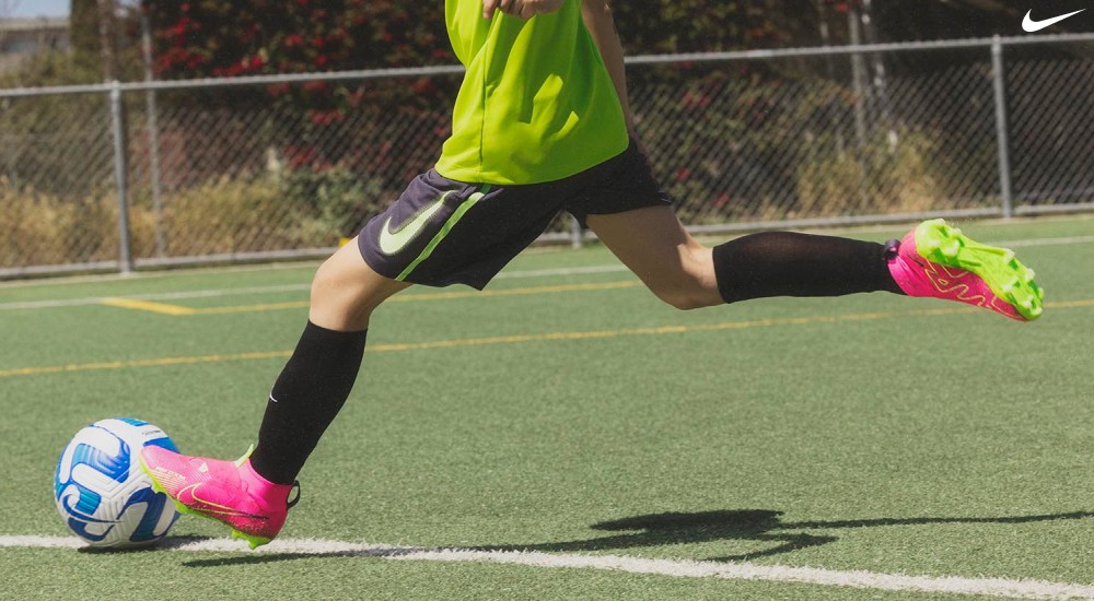 a kid wearing soccer cleats kicking the ball