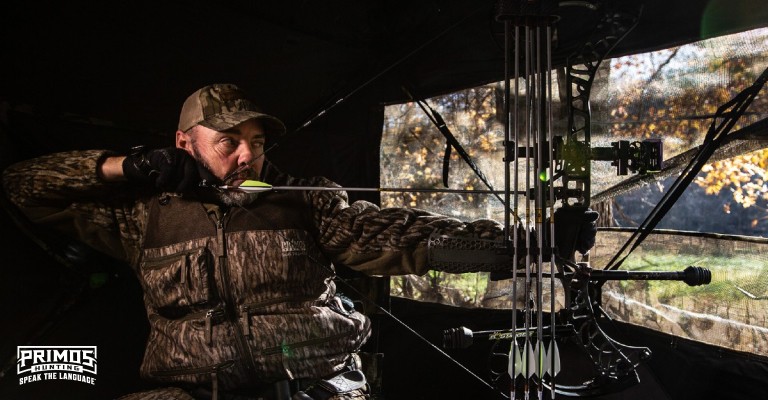 a bowhunter shooting out of a ground blind
